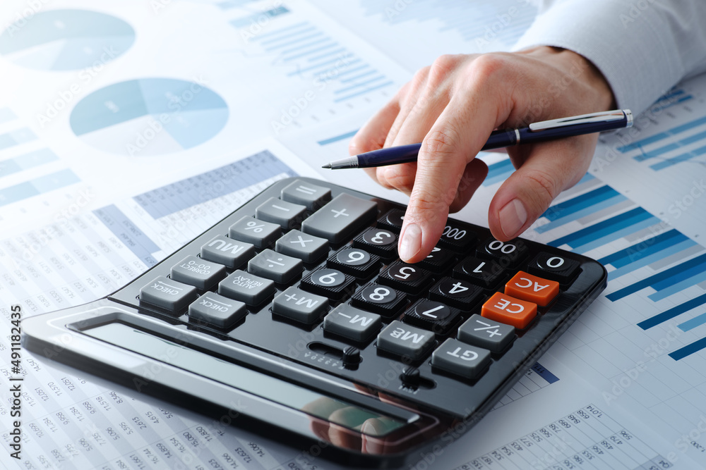 Business person calculating financial data. Close up of hands. Calculator and many reports. Business person calculating financial data. Close up of hands. Calculator and many reports.