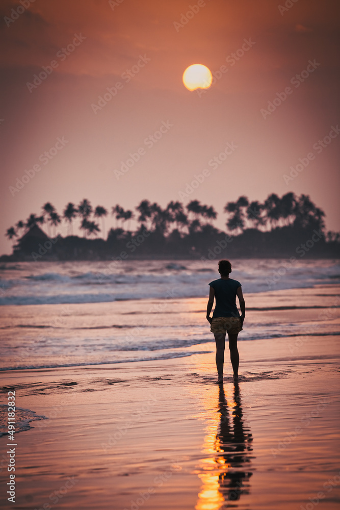 Fototapeta premium woman silhouette walking on sunset beach