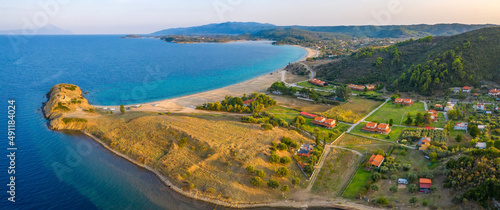 Aerial panorama of a small Greek village on the coast of the Mediterranean sea. Green hills of Peloponnese peninsula, Greece, Europe.