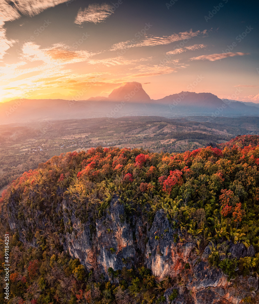 Sunset over mountain range with colorful autumn forest on hill in countryside