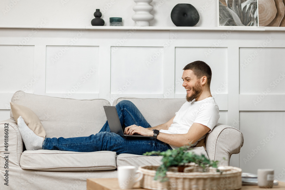 young man at home on sofa with laptop