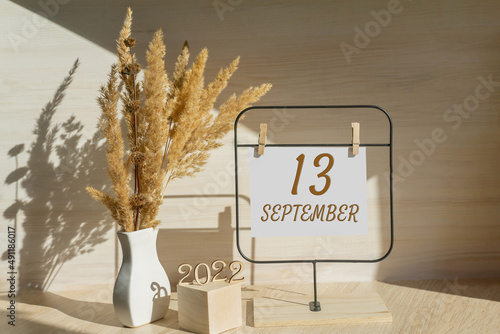 september 13. 13th day of month, calendar date. White vase with dead wood next to the numbers 2022 and stand with an empty sheet of paper on table. Concept of day of year, time planner, autumn month