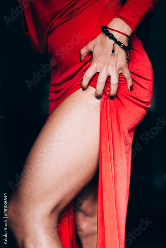 Charming young woman in red sexy dress posing. Photo of attractive legs. obsession with red. Selective focus, filmgrain