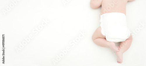 top view of the legs and back of the newborn lying on n white bed.panorama with empty space