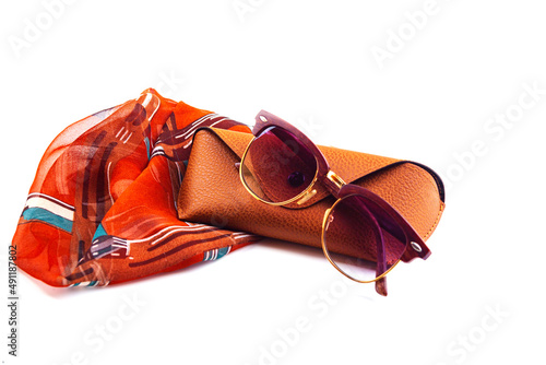 fashionable women's sunglasses. they lie on a woman's scarf. women's jewelry. pink glass. beautiful shape. on a white isolated background. Metal frame. Protect from the sun.