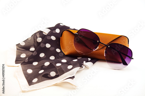 fashionable women's sunglasses. A case for storing glasses. they are lying on a woman's scarf. women's jewelry. pink glass. beautiful shape. on a white isolated background. Metal frame.