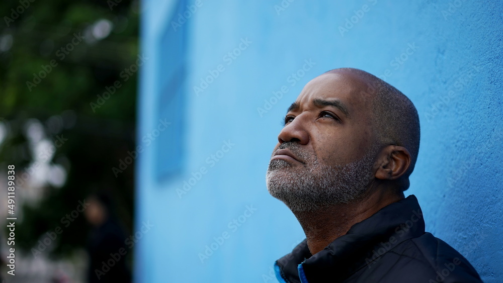 A pensive black senior man thinking about decision standing outside in street A pensive black senior man thinking about decision standing outside in street