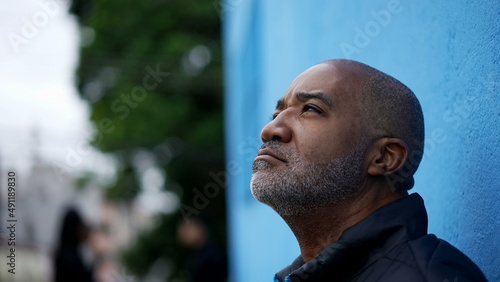 A pensive black senior man thinking about decision standing outside in street
