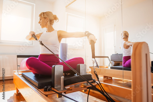 Woman is exercising on pilates reformer bed in her home.