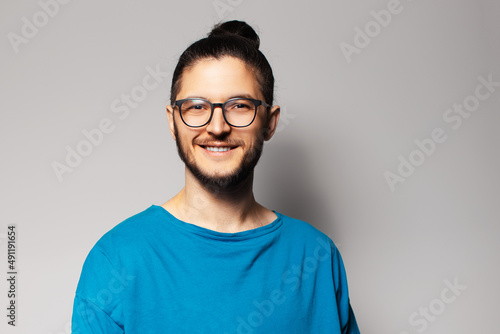 Studio portrait of young smiling man in blue shirt showing on grey background. © Lalandrew