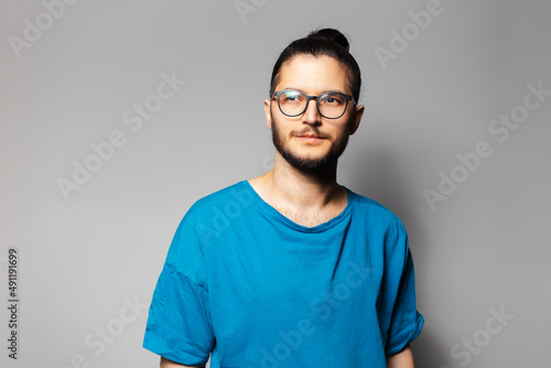 Studio portrait of young serious man in blue shirt on grey background.