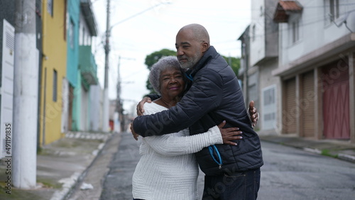A Brazilian son embracing a senior mother in 80s outside portrait