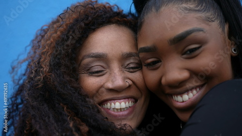 A black mother and daughter faces together smiling