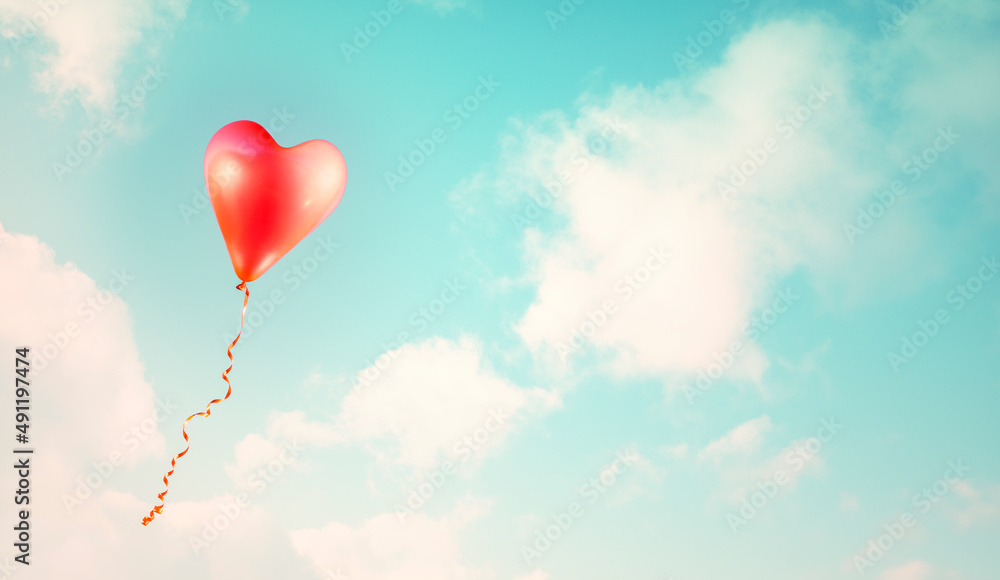 Red heart shaped balloon in a blue sky vintage style background