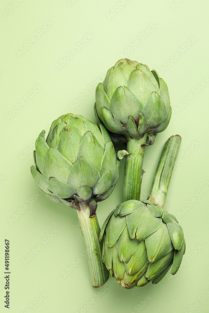 Fototapeta premium Concept of healthy food with artichoke on green background