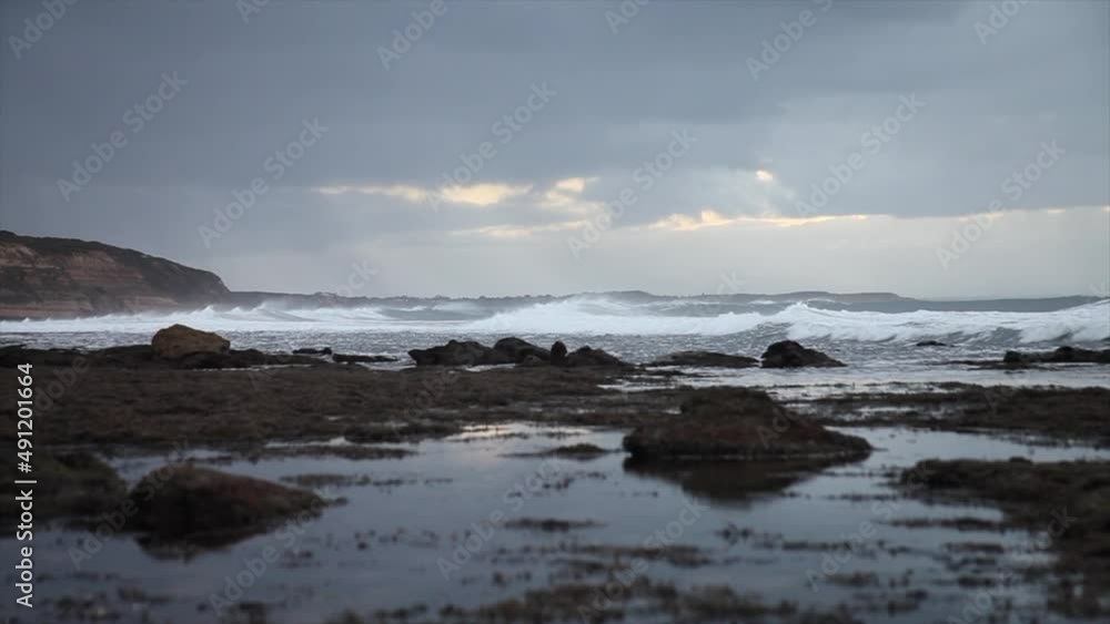 Waves rolling towards shore in the distance with rock pools in the foreground Waves rolling towards shore in the distance with rock pools in the foreground