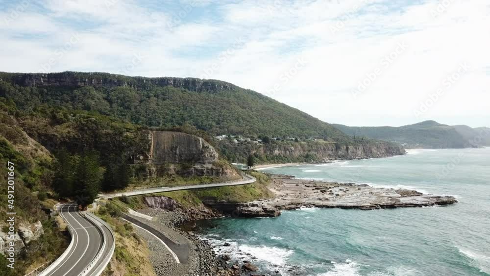 Aerial: Drone flying next to a curvy highway between ocean and cliffs, in New South Wales Australia Aerial: Drone flying next to a curvy highway between ocean and cliffs, in New South Wales Australia