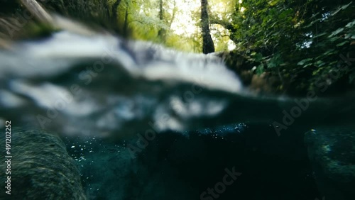 Split-level shot, 50 50, half half video of small waterfall and the under water.  meditation, sanctuary , solace , solitude , tranquillit 
4K video. photo