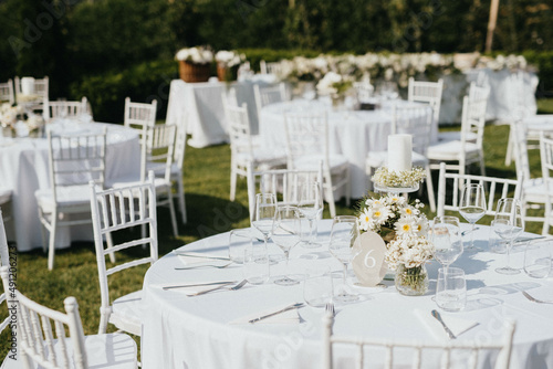 Wedding. Banquet. Chairs and honeymooners table decorated with candles. Beautiful decoration, beautiful flowers.