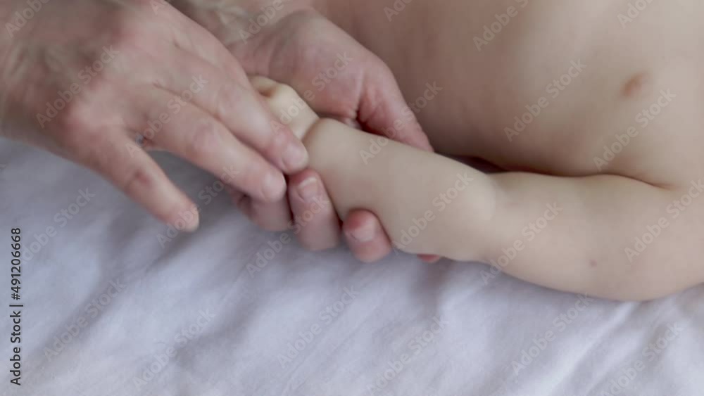 A woman, Masseur, is massaging the hands and chest of a baby boy. no clothes toddler on a table with white blanket. cute little child is very calm and relaxed, enjoying the massage. no tense muscles. A woman, Masseur, is massaging the hands and chest of a baby boy. no clothes toddler on a table with white blanket. cute little child is very calm and relaxed, enjoying the massage. no tense muscles.