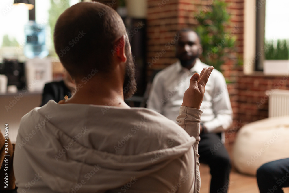 Fototapeta premium Person sharing health progress with group of people at aa meeting, sitting in circle. Man at therapy session talking about alcohol addiction with rehab patients and psychotherapist.