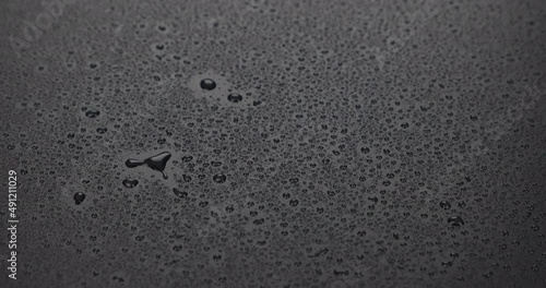 Raindrops falling on a black surface. The beginning of the rain