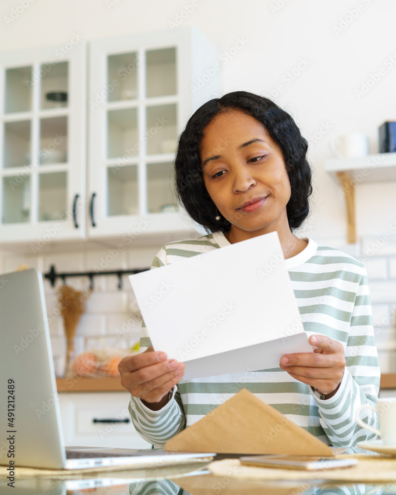 Young african-american female opening and reading letter. Concept of receiving mail correspondence Young african-american female opening and reading letter. Concept of receiving mail correspondence