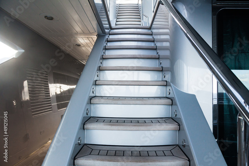 Access to the next floor of the yacht with a wooden staircase  railings and a closing hatch. Internal staircase on the yacht with handrails. Yacht interior with ladder.