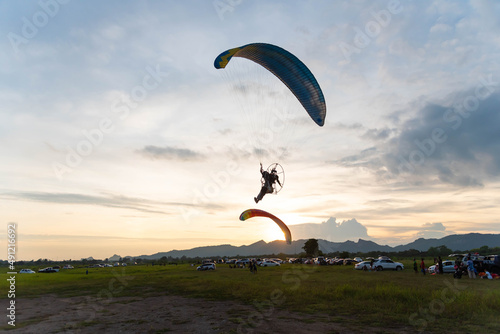 paraglider fly with paramotor flying in the air on a sunset with an Mountain and horizon in the background with a giant sun