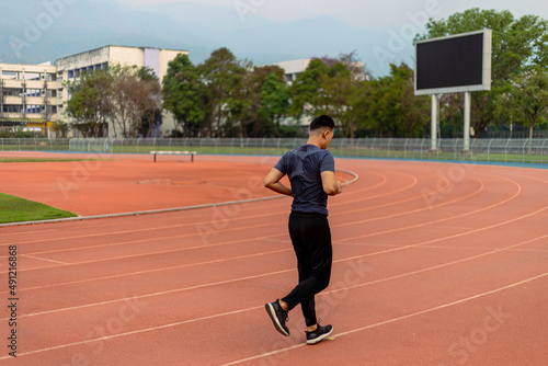 Sports and recreation concept a young male adult running in low speed in the sports stadium as his healthy routine in the evening