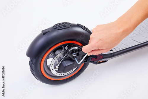 Hand repairing electrical scooter on white background. Repair service for fixing electrical escooters. Technological concept. photo