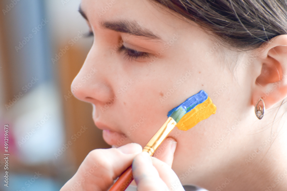 Portrait of Ukrainian girl with national flag on cheek, patriot of Ukraine teen girl. Portrait of Ukrainian girl with national flag on cheek, patriot of Ukraine teen girl.