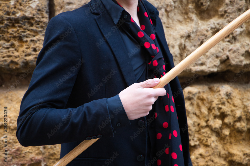 gypsy man dancing flamenco, young and handsome dressed in black and red shoes and a wooden cane is posing on a background of a stone wall. Flamenco cultural heritage of humanity gypsy man dancing flamenco, young and handsome dressed in black and red shoes and a wooden cane is posing on a background of a stone wall. Flamenco cultural heritage of humanity