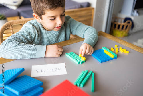 Little boy using the base 10 method to do addition at home