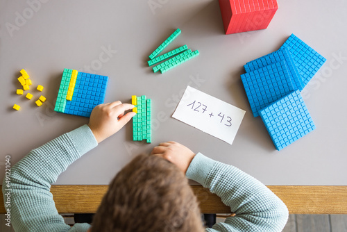 Little boy using the base 10 method to do addition at home photo