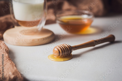 Milk and honey. Glass cup with milk and bowl with honey on the table. Spoon for honey. Breakfast, snack. Calming and healthy drink.