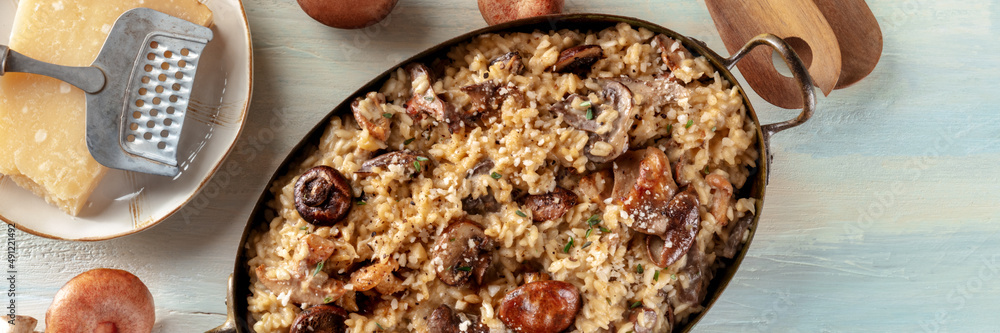 Risotto ai funghi panorama, mushroom and cheese rice panoramic banner, with ingredients, overhead flat lay shot on a wooden background Risotto ai funghi panorama, mushroom and cheese rice panoramic banner, with ingredients, overhead flat lay shot on a wooden background