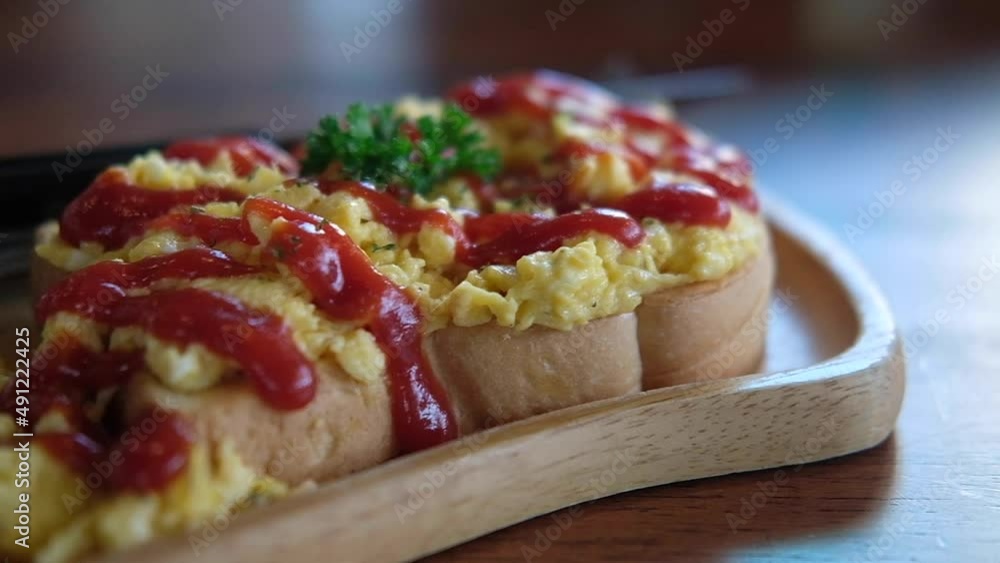 Panning shot of scrambled eggs on toasted bread with ketchup, breakfast in morning at home.
Panning shot of scrambled eggs on toasted bread with ketchup, breakfast in morning at home.