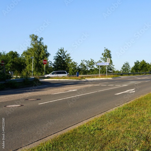 View of empty road in Itzehoe, Germany with traffic direction sign to Hamburg and trees in clear blue sky background. No people. photo