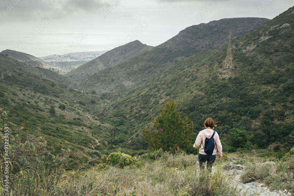 Female backpacker hiker. Descending from the abrupt Mediterranean mountain.