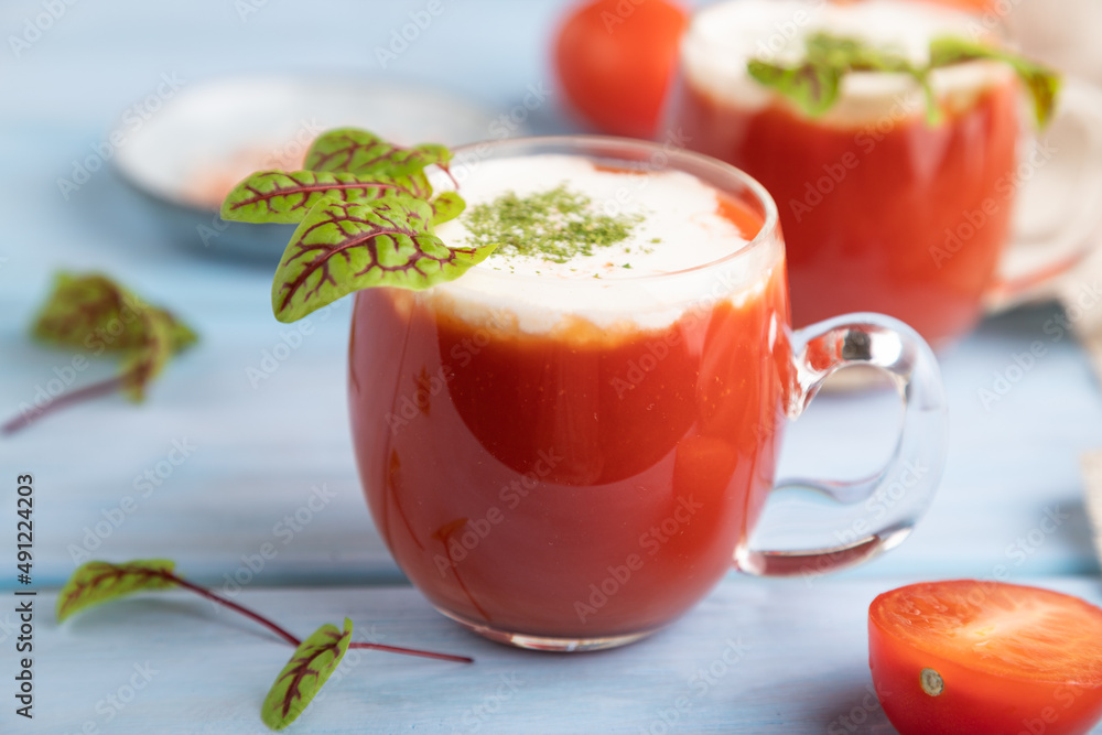 Tomato juice with sorrel, salt and sour cream in glass on blue wooden background. Side view, selective focus. Tomato juice with sorrel, salt and sour cream in glass on blue wooden background. Side view, selective focus.