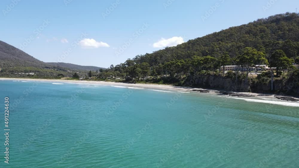 Drone aerial parralax over tropical blue ocean showing nature and residential homes on beach front Drone aerial parralax over tropical blue ocean showing nature and residential homes on beach front
