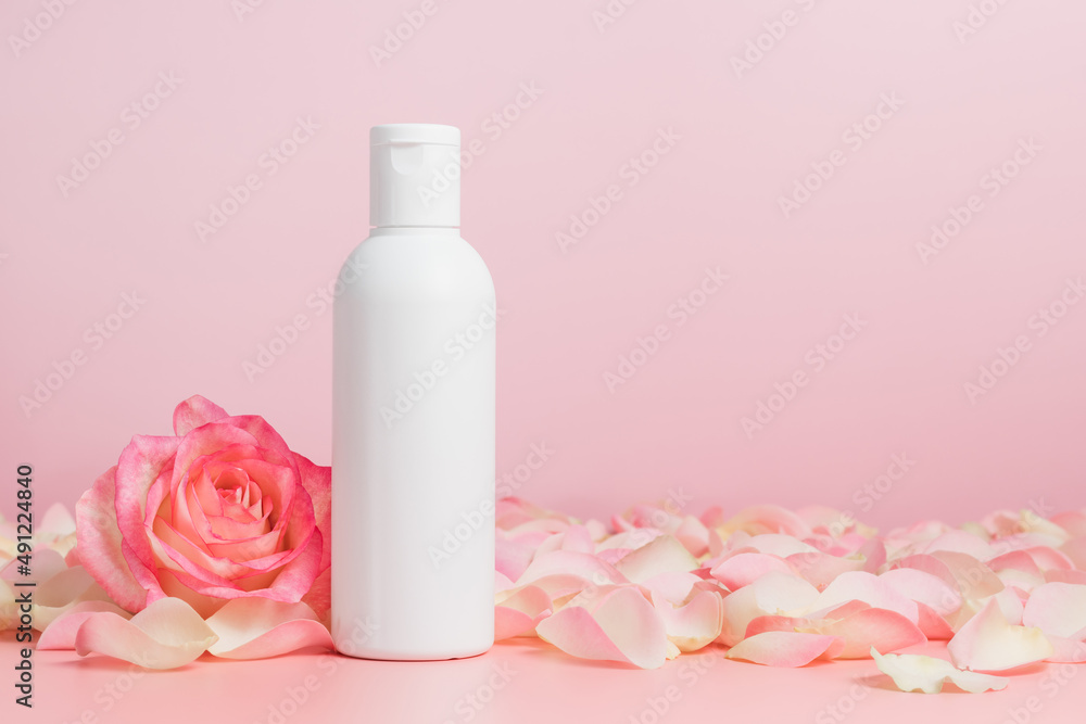 White unbranded mockup bottle of body lotion or shampoo with roses and petals, bottle for logo or design, natural cosmetic White unbranded mockup bottle of body lotion or shampoo with roses and petals, bottle for logo or design, natural cosmetic