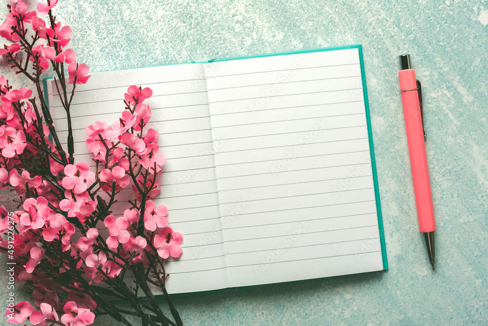 Naklejka premium Top view of blank journal open with copy space, pink pen and almond blossoms