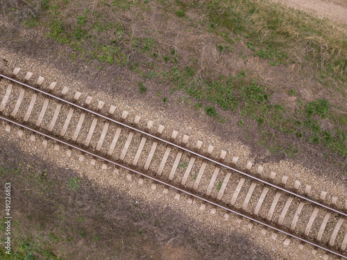 Aerial view of railway track through countryside, drone top view pov of rails as abstract background