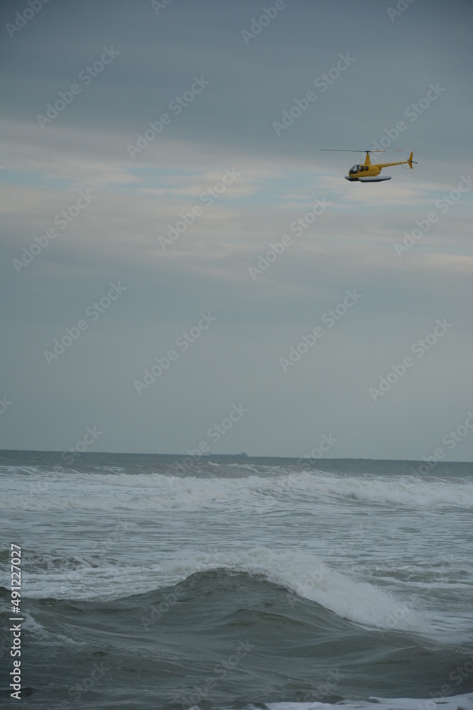 Fototapeta premium helicopter soaring over the waves and the beach