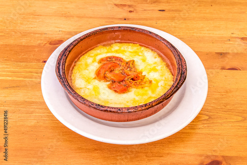 Gran receta italiana para una porción de queso provolone a la parrilla en una olla de barro con tomate y pimiento picado en el centro de la comida