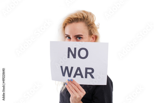 A young woman covers her face with a no war poster