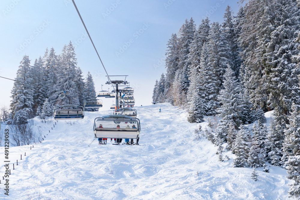 Modern chair lift in the skiing resort during winter vacation. Snow covered trees and a natural skiing slope. Modern chair lift in the skiing resort during winter vacation. Snow covered trees and a natural skiing slope.
