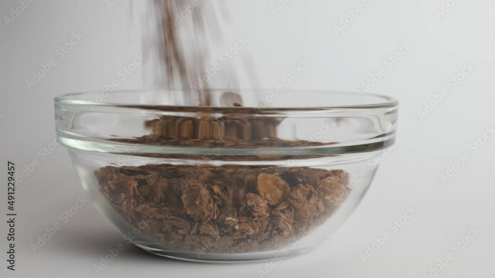 Granola is poured into a transparent bowl on a white background. Healthy food. Granola is poured into a transparent bowl on a white background. Healthy food.